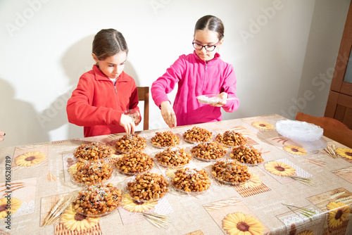 Sorelle gemelle di nove anni intente nel guarnire un dolce tipico natalizio.