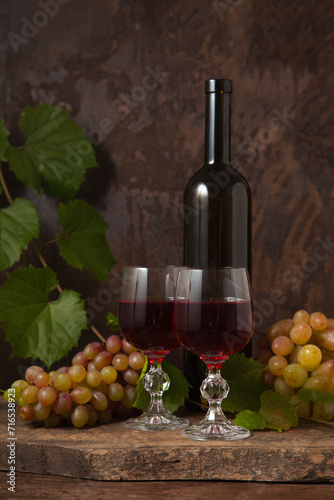 Still life with glasses of red wine and grapes on vintage wooden background..