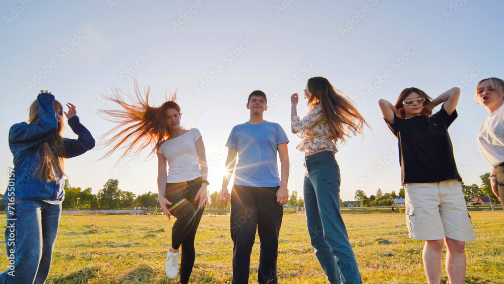 Funny jolly friends dancing in the city meadow in the evening. Funny jolly friends dancing in the city meadow in the evening.