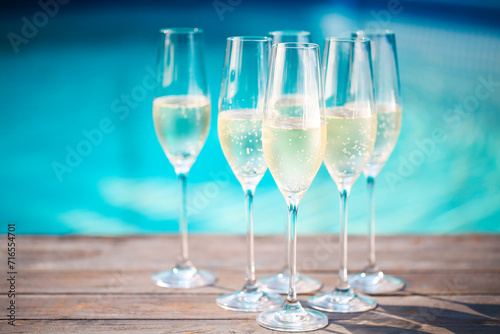 Champagne glasses on wooden background near pool