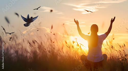 Woman praying and free bird enjoying nature on sunset background  hope concept