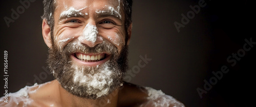 Close-up, bearded man and shaving foam in studio for personal grooming, grooming and facial hygiene with a smile. Dark background. Copy space photo