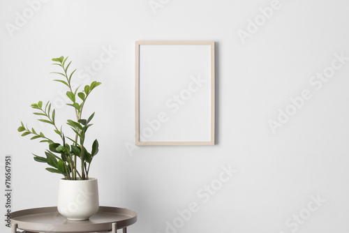 Wooden frame mockup on the wall with a zamia flower decoration. photo