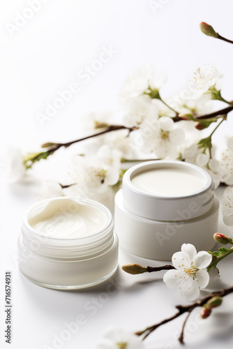 Cosmetic cream jars mockup on white background with spring flowers. Skin care product package design.