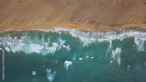Overhead aerial view of ocean waves splash against desert sand beach Playa de Cofete, Jandia Peninsula on Fuerteventura, Canary Islands, Spain photo