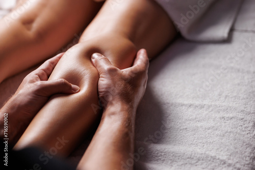 Male masseurs hands press female visitors leg, relaxing massage in spa salon. Body care for young woman.Therapeutic procedure for an injured leg, restoration of health.