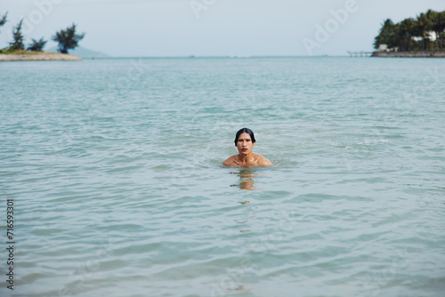Smiling Asian Man Enjoying a Refreshing Swim at a Tropical Beach, Embracing the Freedom of a Relaxing Summer Vacation