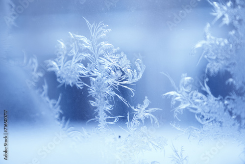 Close up of an abstract blurred frosty patterns on the glass, window with copy space. Blue ice winter background, natural texture.
