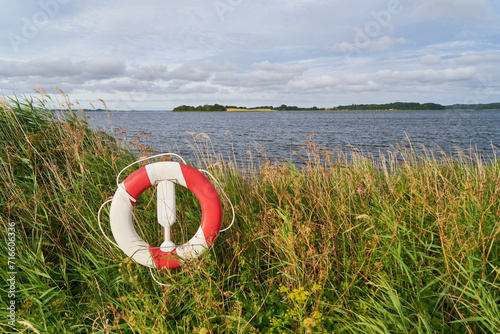 Life ring as livesaver on shoreline near lake for emergency rescue photo