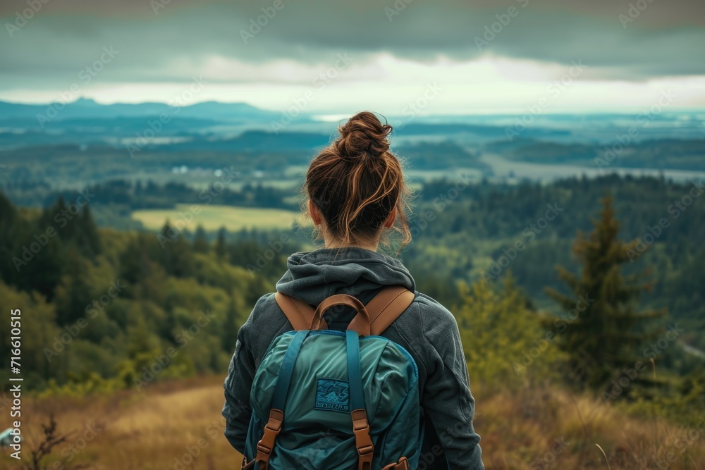 A woman with a backpack looks at the landscape. A woman in a mountain landscape