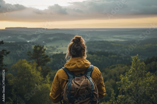 A woman with a backpack looks at the landscape. A woman in a mountain landscape