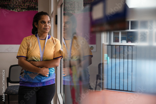 Aboriginal woman wearing lanyard looking out window photo