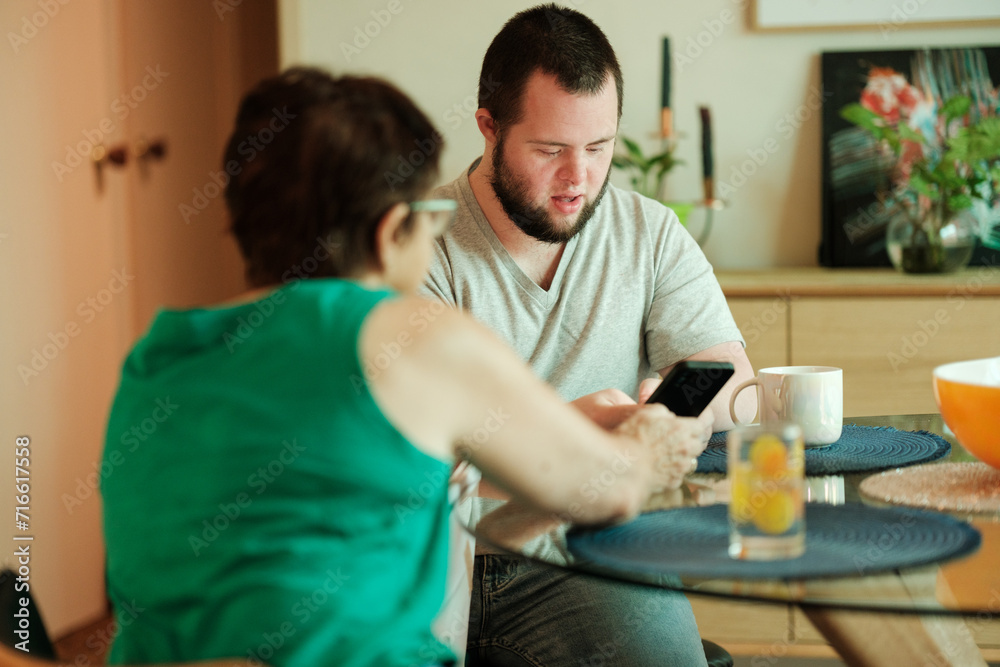Young Man with Down Syndrome Being Helped with Smartphone Young Man with Down Syndrome Being Helped with Smartphone