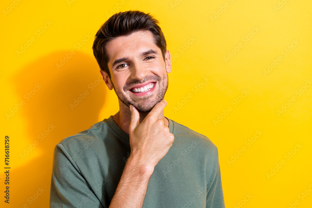 Photo of toothy beaming good mood man with bristle dressed khaki t-shirt keep arm on chin smiling isolated on yellow color background Photo of toothy beaming good mood man with bristle dressed khaki t-shirt keep arm on chin smiling isolated on yellow color background
