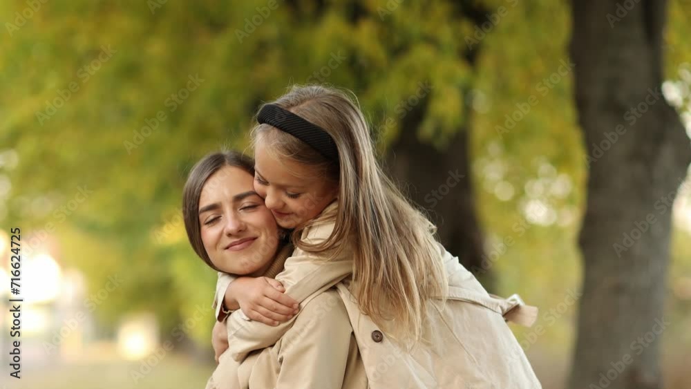 Family day. Young mom and little daughter having fun and enjoy relaxing outdoors in autumn park. Adorable child girl tightly hugs and kiss her mother. Maternal care and love for kid. Mothers day. Family day. Young mom and little daughter having fun and enjoy relaxing outdoors in autumn park. Adorable child girl tightly hugs and kiss her mother. Maternal care and love for kid. Mothers day.