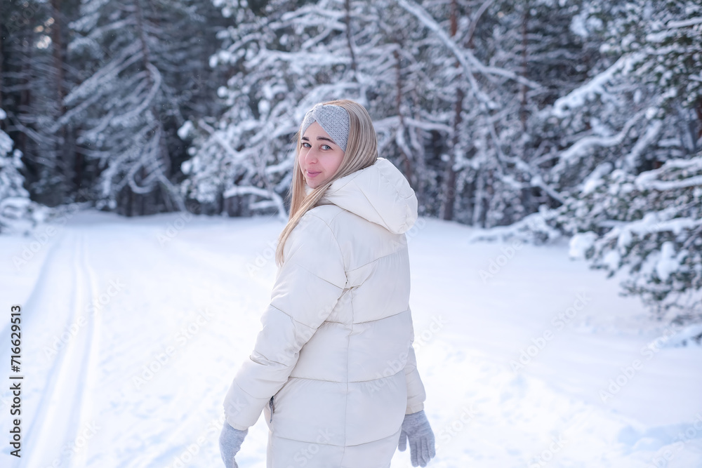 A woman in a white jacket and hat standing in the snow. A woman in a white jacket and hat standing in the snow.