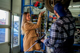 In the workshop, a woman client and a mechanic with tools, discussing car troubles. A scene of communication and guidance.