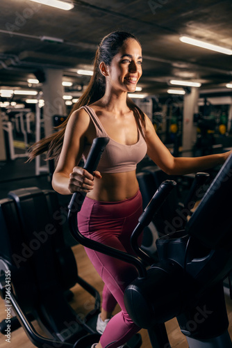 A sportswoman exercising on ski machine in a gym.