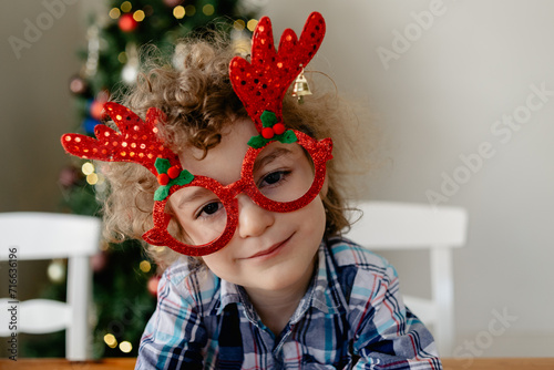 Happy, young boy wearing novelty glasses celebrating Christmas at home in Australia