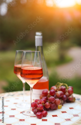 Two glasses and bottle of rose wine in autumn vineyard on marble table