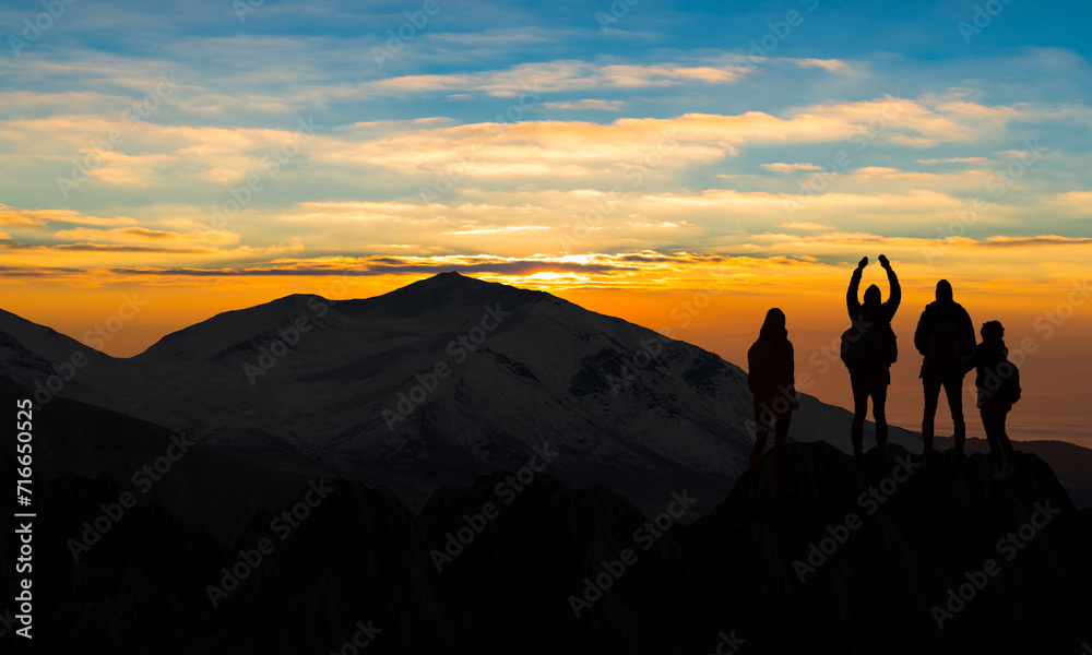 Hiking family Silhouette on top of mountain against sunset. Happy People Standing on too hill. Copy space.  