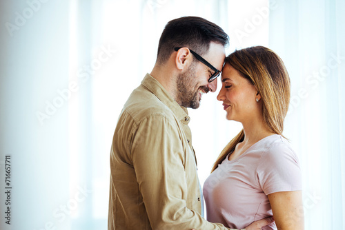 Beautiful couple hugging and looking at each other. Close-up portrait of a caucasian young loving couple embracing. Happy millennial husband and wife hug cuddle enjoy tender romantic moment