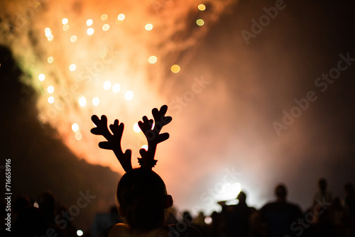 person wearing reindeer antlers watching fireworks photo