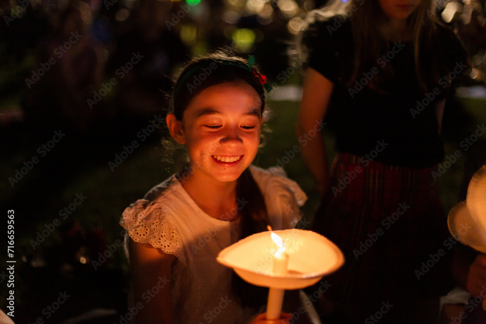 teen girl grinning and looking at her candle at carols by candlelight teen girl grinning and looking at her candle at carols by candlelight