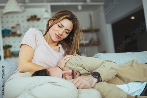 Mand and woman couple hugging each other lying on sofa at home. Couple at home relaxing in sofa. Happy married young couple hugging, sitting on cozy couch together
