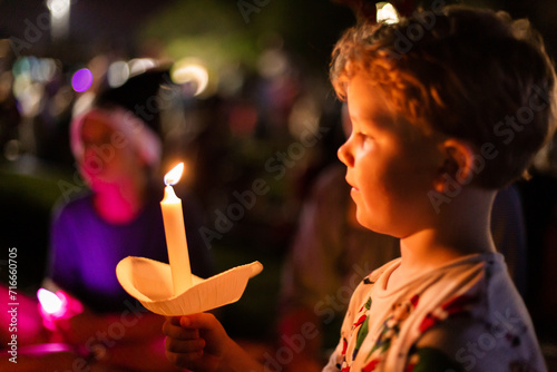 child holding a candle at a carols event at night photo