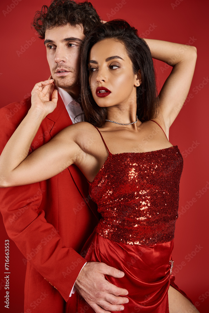 young brunette woman with red lips posing near handsome man in formal wear on red background young brunette woman with red lips posing near handsome man in formal wear on red background