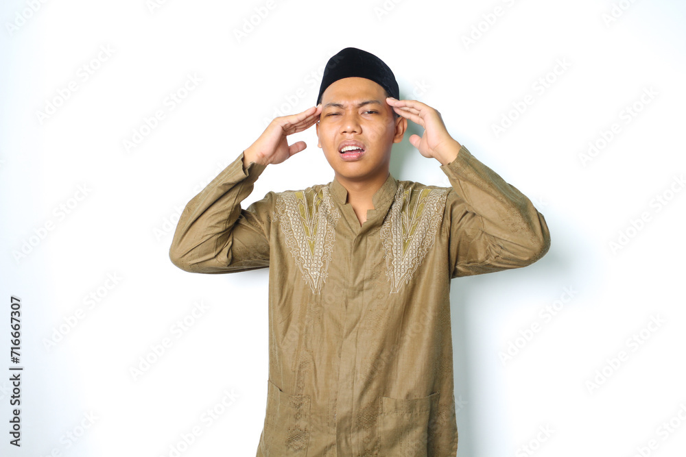 stressed asian muslim man wearing koko clothes hold his head feeling dizzy isolated on white background stressed asian muslim man wearing koko clothes hold his head feeling dizzy isolated on white background