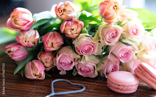 Beautiful pink bouquet of flowers and fine delicacies on dark wood. Sweet pastries with roses and tulips. Concept background for wedding celebrations and mother's day.