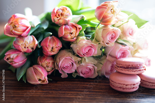 Beautiful pink bouquet of flowers and fine delicacies on dark wood. Sweet pastries with roses and tulips. Concept background for wedding celebrations and mother's day.