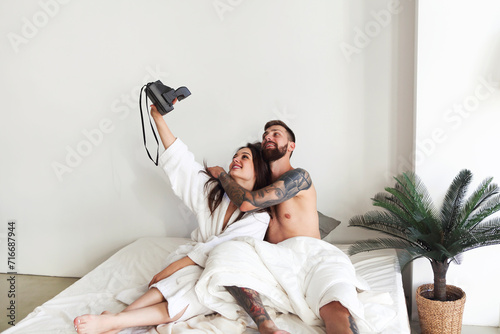 Couple posing in bed and taking selfie in morning © Dasha Petrenko