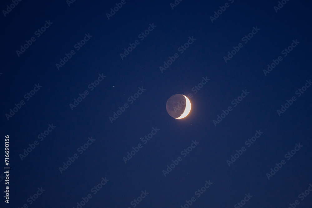 Natural satellite of the earth. Young crescent moon on a clear sky at the end of the day in the summer Natural satellite of the earth. Young crescent moon on a clear sky at the end of the day in the summer