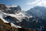 A hiker traversing a snowy mountain landscape under a clear sky