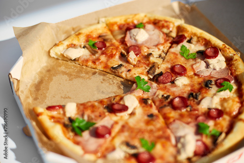 A freshly baked pizza with sliced tomatoes, cheese, mushrooms, and herbs is missing two slices, suggesting a shared meal at an outdoor picnic.