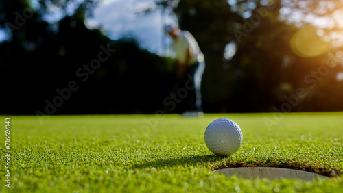 Golfer putting ball on the green golf, lens flare on sun set evening time.