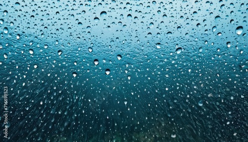  drops of water on a window pane with a green field in the back ground and a blue sky in the back ground, with a green field in the foreground.