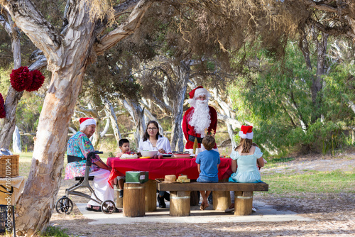 family enjoying Christmas lunch in a shady seaside park photo
