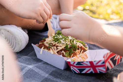 children sharing a baked potato from a food truck on a picnic blanket photo