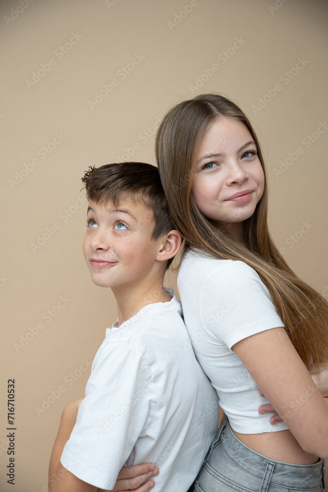 beautiful pretty 14 years old girl with her cute and cool 11 years old brother in front of brown background, brother and sister love beautiful pretty 14 years old girl with her cute and cool 11 years old brother in front of brown background, brother and sister love