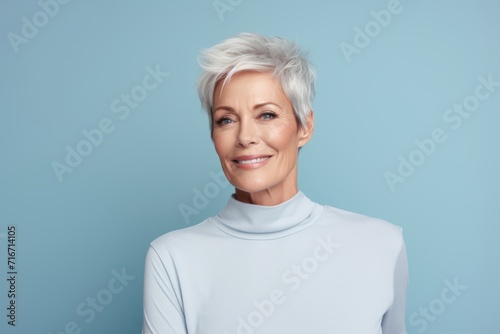 Portrait of a merry woman in her 50s sporting a long-sleeved thermal undershirt against a pastel blue background. AI Generation