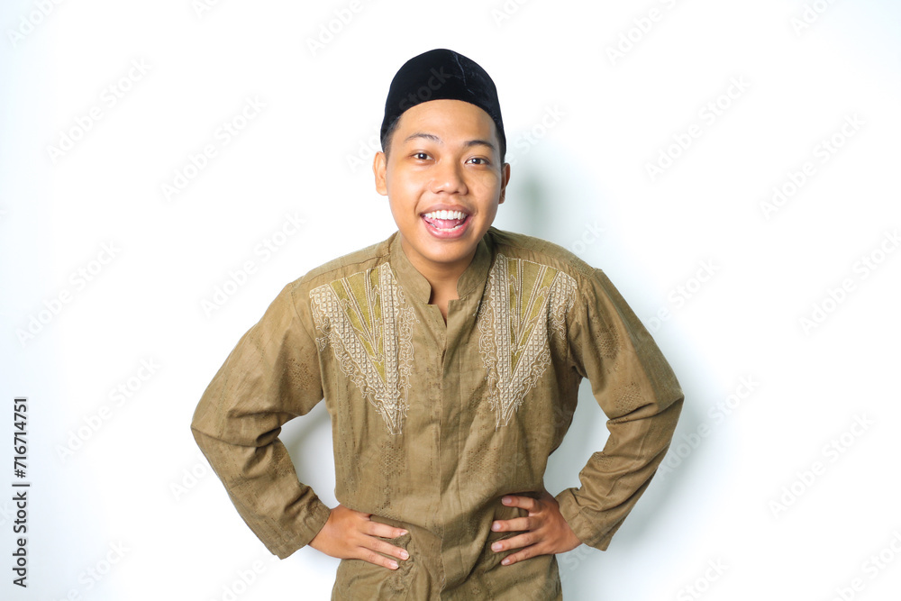 excited asian muslim man wearing islamic dress looking at camera with hands on waist isolated on white background excited asian muslim man wearing islamic dress looking at camera with hands on waist isolated on white background