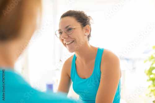 A woman patient talks cheerful to her physiotherapist after receiving a manual therapy session