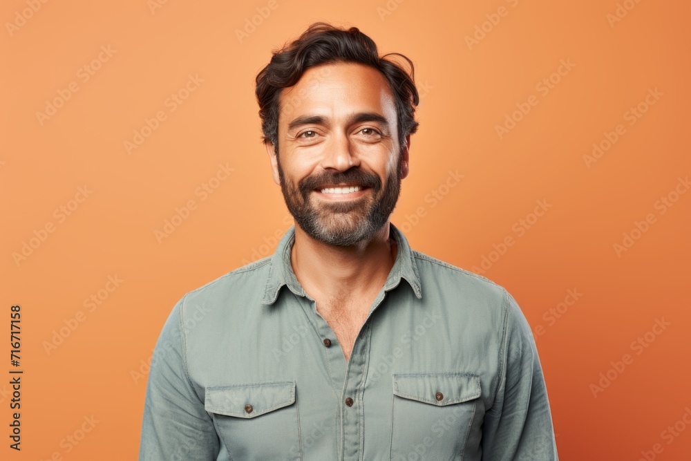 Obraz premium Portrait of a jovial man in his 30s sporting a versatile denim shirt against a pastel orange background. AI Generation
