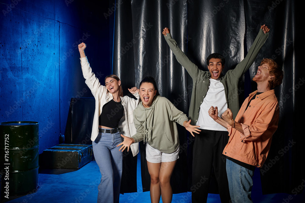 group of young multicultural friends celebrating success after solving mystery in escape room