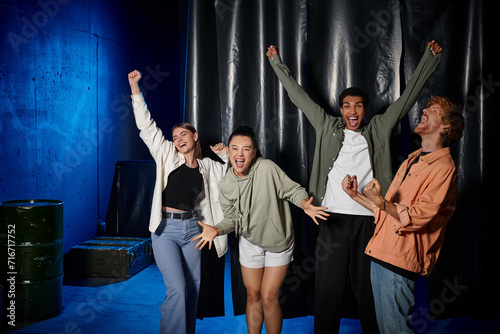 group of young multicultural friends celebrating success after solving mystery in escape room