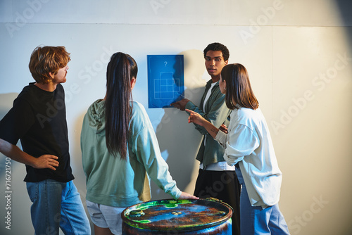 african american man finding clue near interracial friends during quest in escape room, mystery